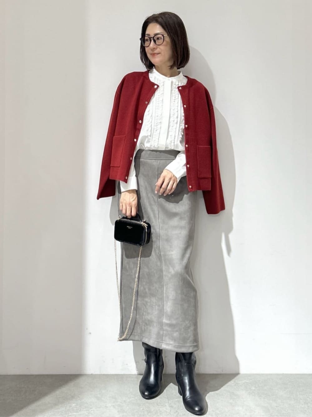 レッド系のカーディガン/ボレロ、ホワイト系のシャツ/ブラウス、グレー系のスカートを着用したレディースの秋コーディネートの1枚目の写真