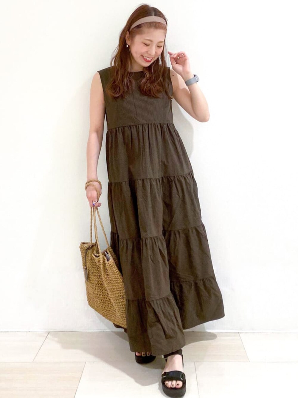 ブラウン系のワンピース、ベージュ系のトートバッグ、ブラック系のサンダルを着用したレディースの夏コーディネートの1枚目の写真