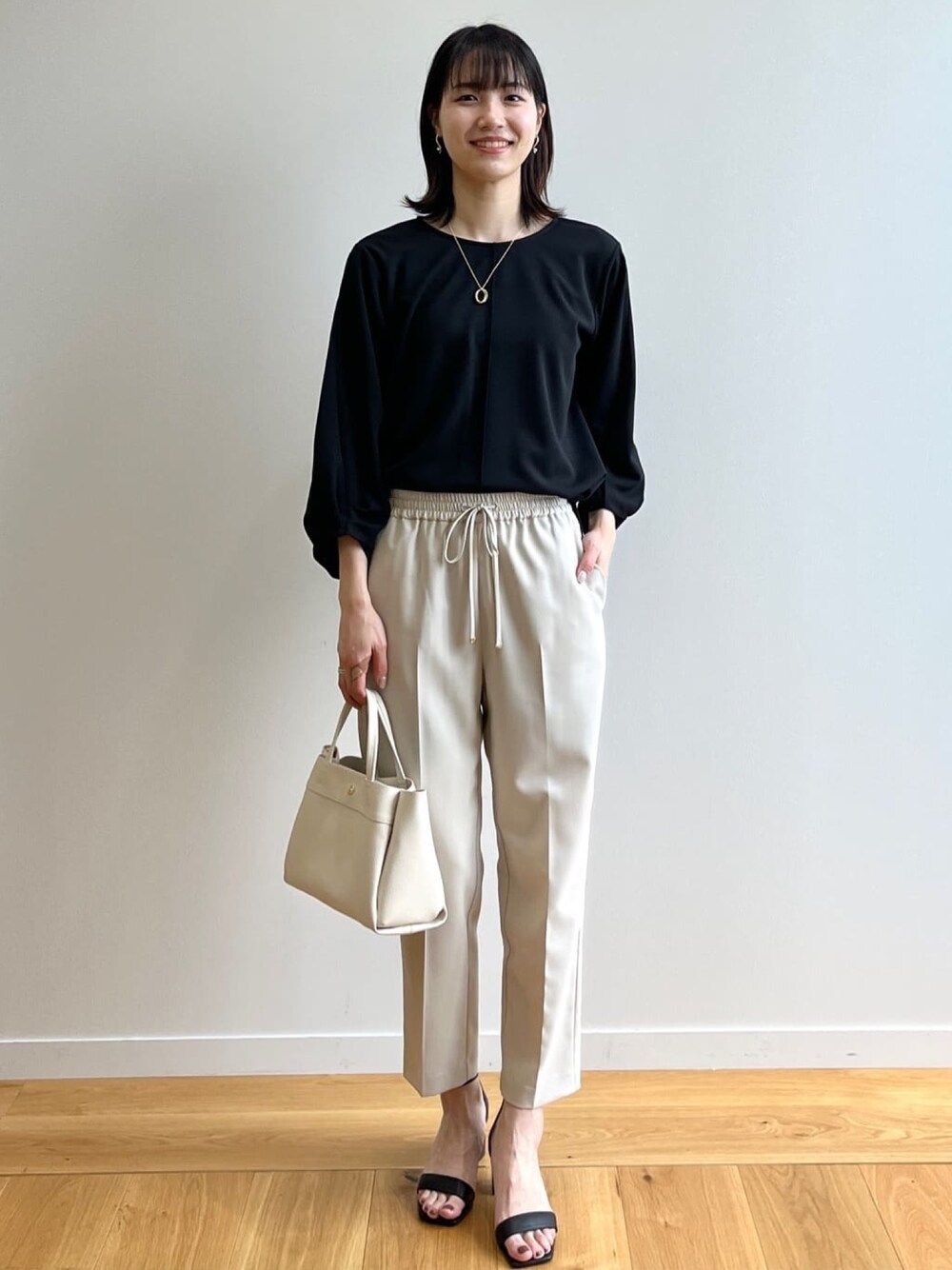 ブラック系のTシャツ/カットソー、ベージュ系のその他パンツ、ブラック系のサンダルを着用したレディースの春コーディネートの1枚目の写真