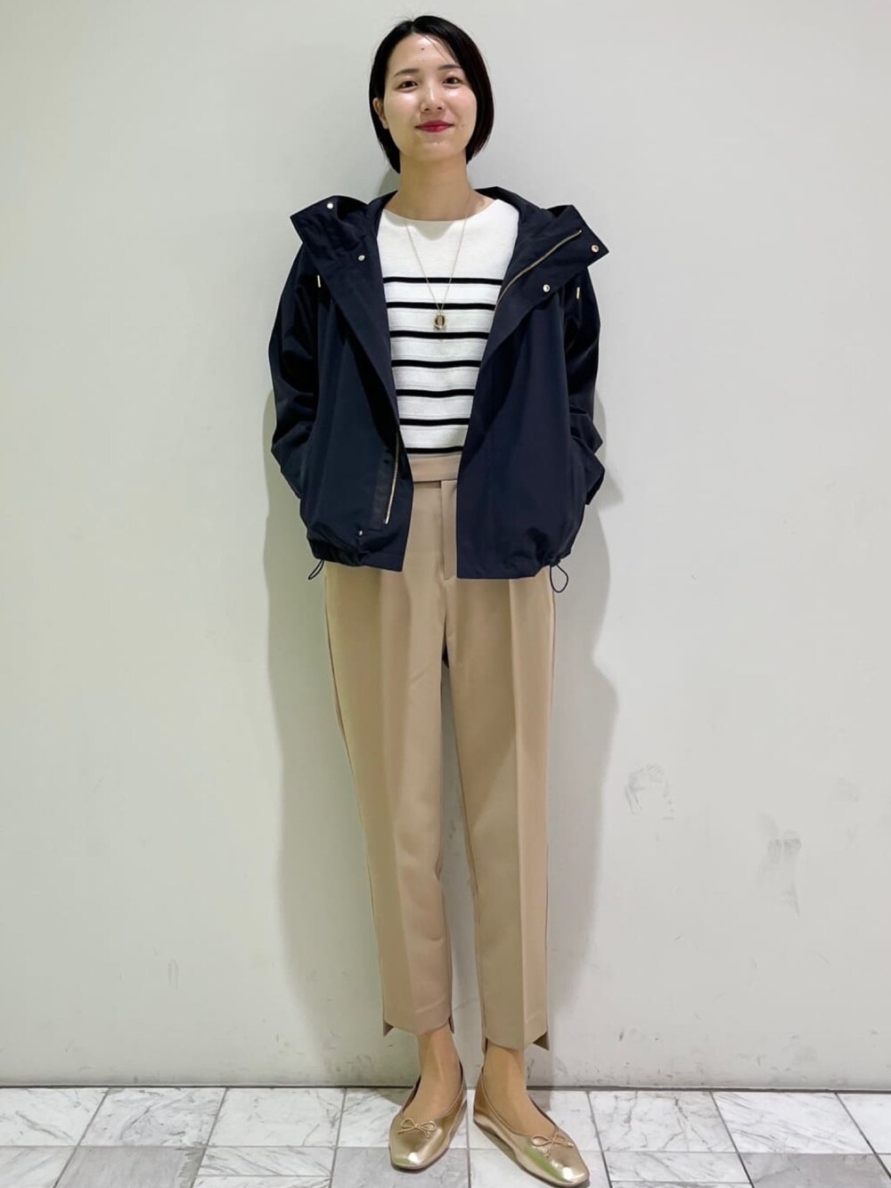 ベージュ系のその他パンツ、ゴールド系のその他シューズ、ホワイト系のニット/セーターを着用したレディースの春コーディネートの1枚目の写真