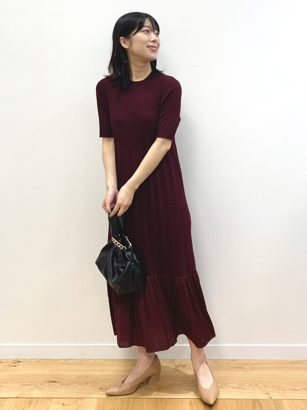 レッド系のワンピース、ブラック系のハンドバッグ、ベージュ系のパンプスを着用したレディースの夏コーディネートの1枚目の写真