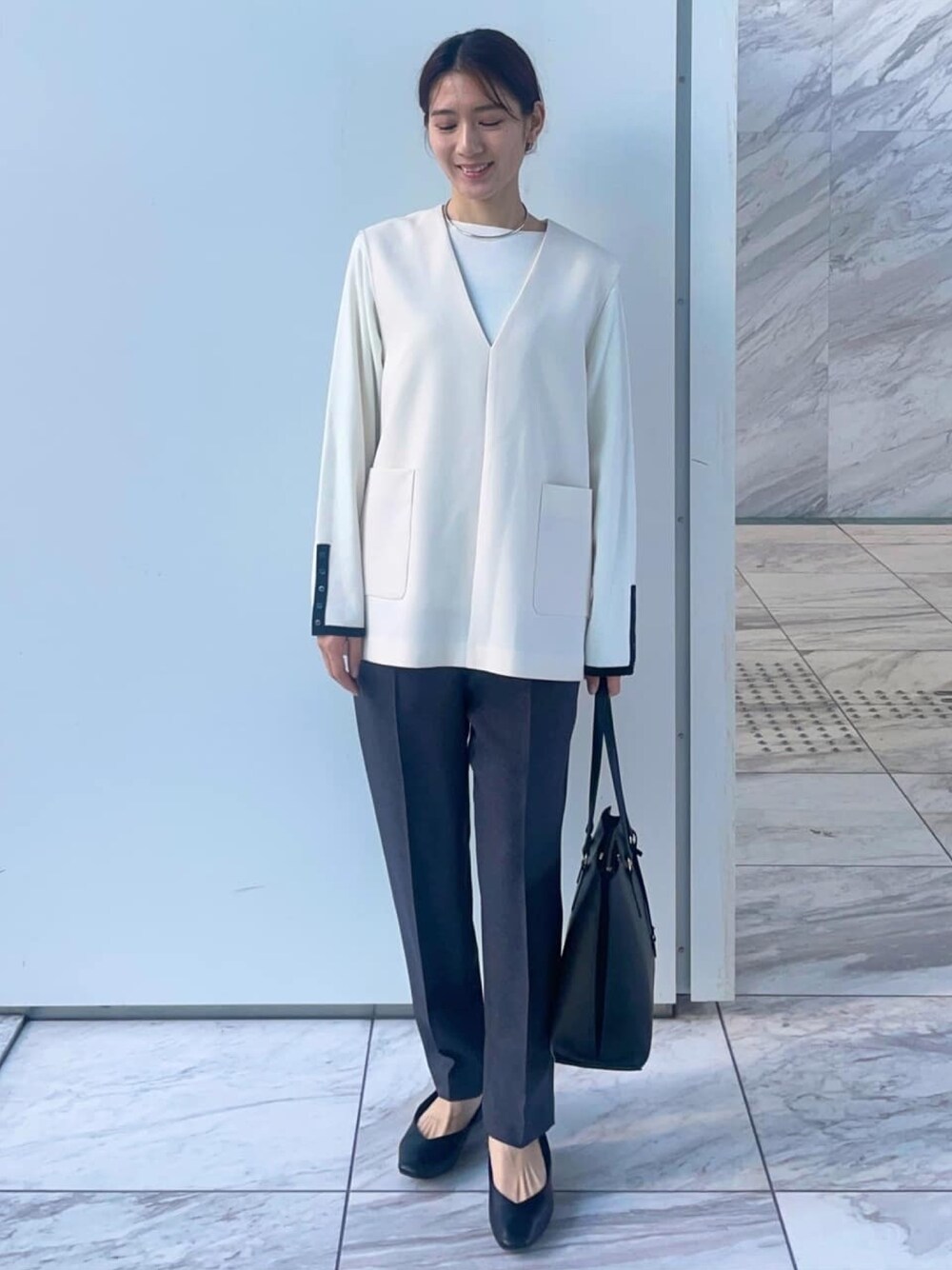 ホワイト系のニット/セーター、ホワイト系のベスト、ブラック系のトートバッグを着用したレディースの冬コーディネートの1枚目の写真