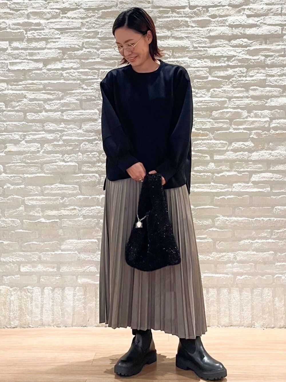 ブラック系のTシャツ/カットソー、グレー系のスカート、ブラック系のハンドバッグを着用したレディースの秋コーディネートの1枚目の写真