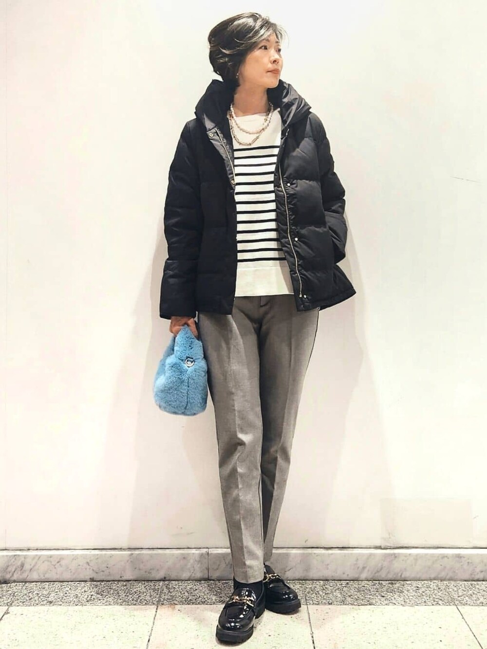 ブラック系のダウンジャケット/コート、ホワイト系のニット/セーター、グレー系のその他パンツを着用したレディースの秋コーディネートの1枚目の写真