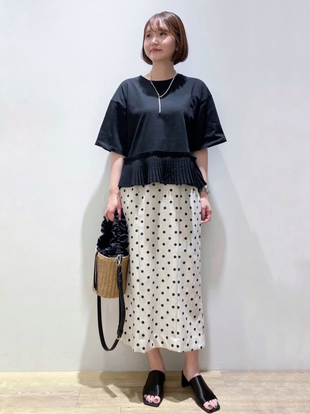 ベージュ系のスカート、ブラック系のTシャツ/カットソー、ブラック系のサンダルを着用したレディースの夏コーディネートの1枚目の写真