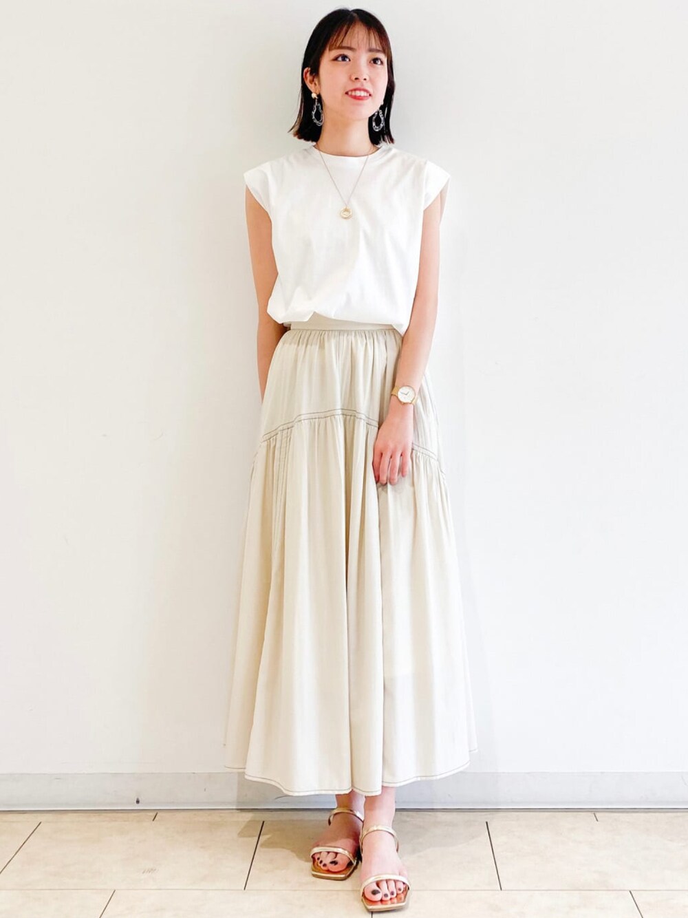 ホワイト系のTシャツ/カットソー、ホワイト系のスカート、ゴールド系のネックレスを着用したレディースの夏コーディネートの1枚目の写真