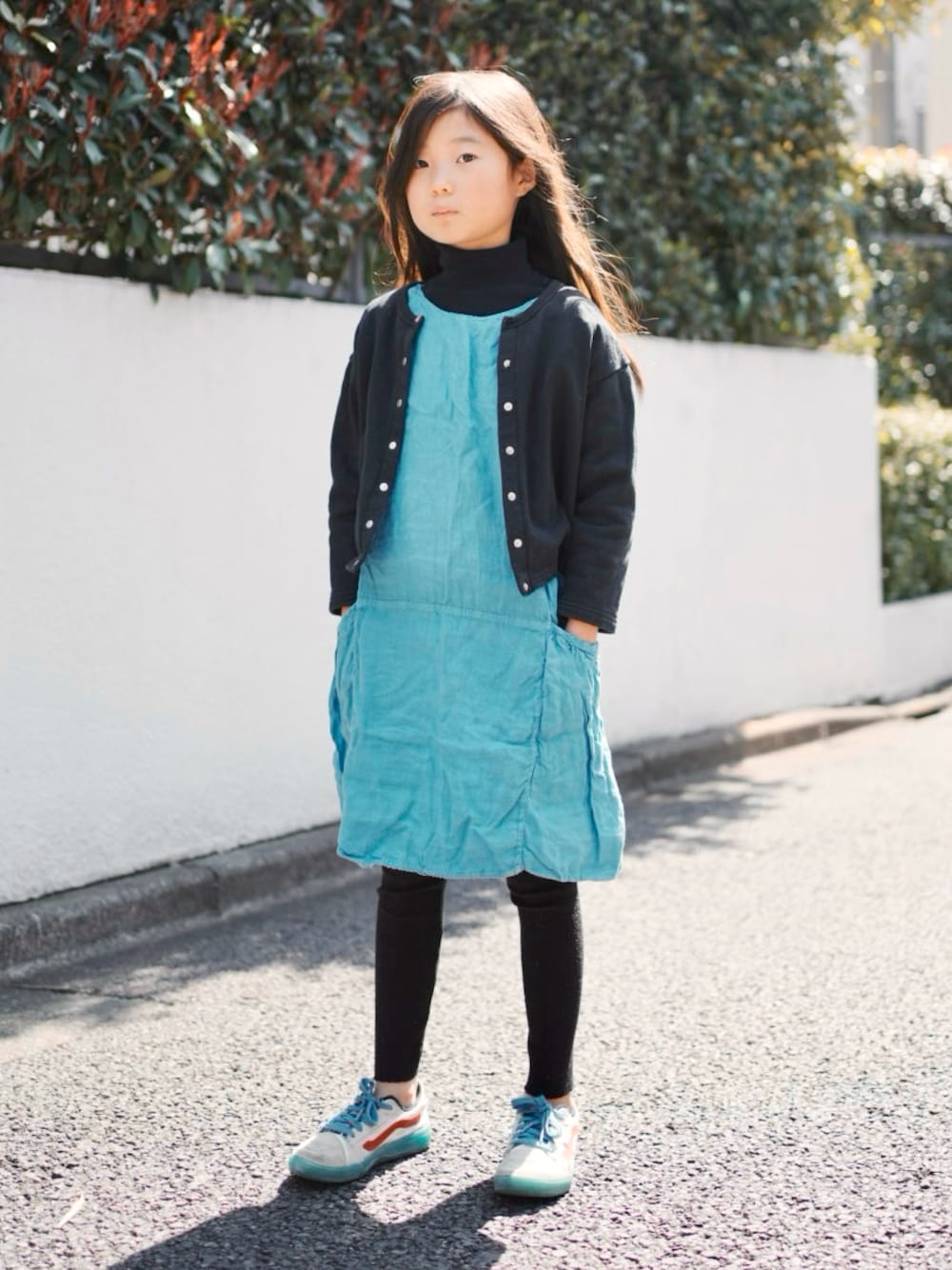 ブラック系のカーディガン/ボレロ、ブルー系のワンピース、ホワイト系のスニーカーを着用したキッズの春コーディネートの1枚目の写真