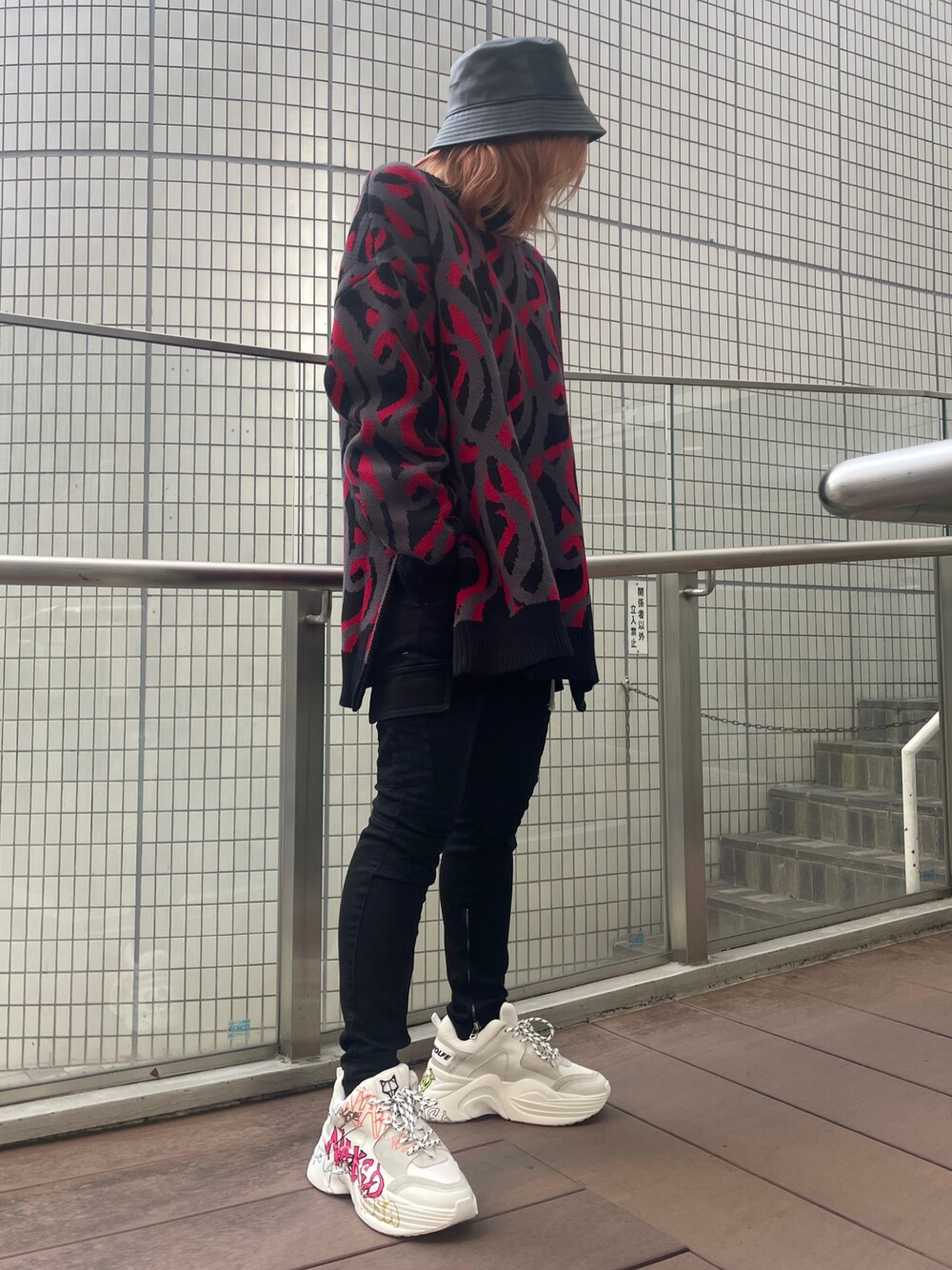 レッド系のニット/セーター、ブラック系のカーゴパンツ、ホワイト系のスニーカーを着用したレディースの秋コーディネートの1枚目の写真