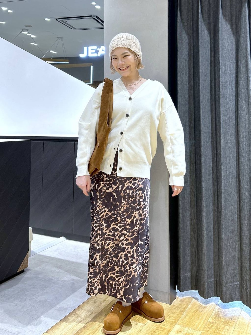 ブラウン系のその他シューズ、ブラウン系のトートバッグ、ホワイト系のカーディガン/ボレロを着用したレディースの秋コーディネートの1枚目の写真