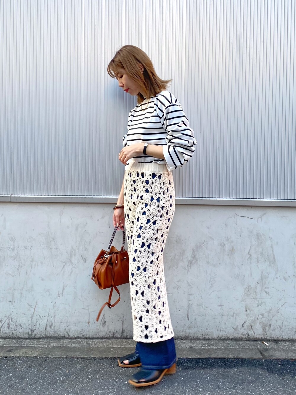 ブラック系のニット/セーター、ホワイト系のスカート、ブルー系のデニムパンツを着用したレディースの冬コーディネートの2枚目の写真