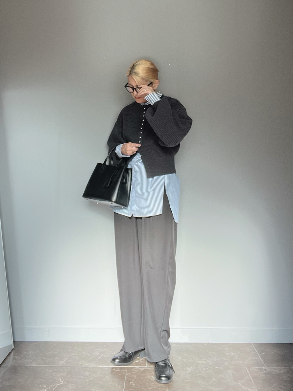 グレー系のカーディガン/ボレロ、ブラック系のその他パンツ、ブラック系のハンドバッグを着用したレディースの秋コーディネートの1枚目の写真