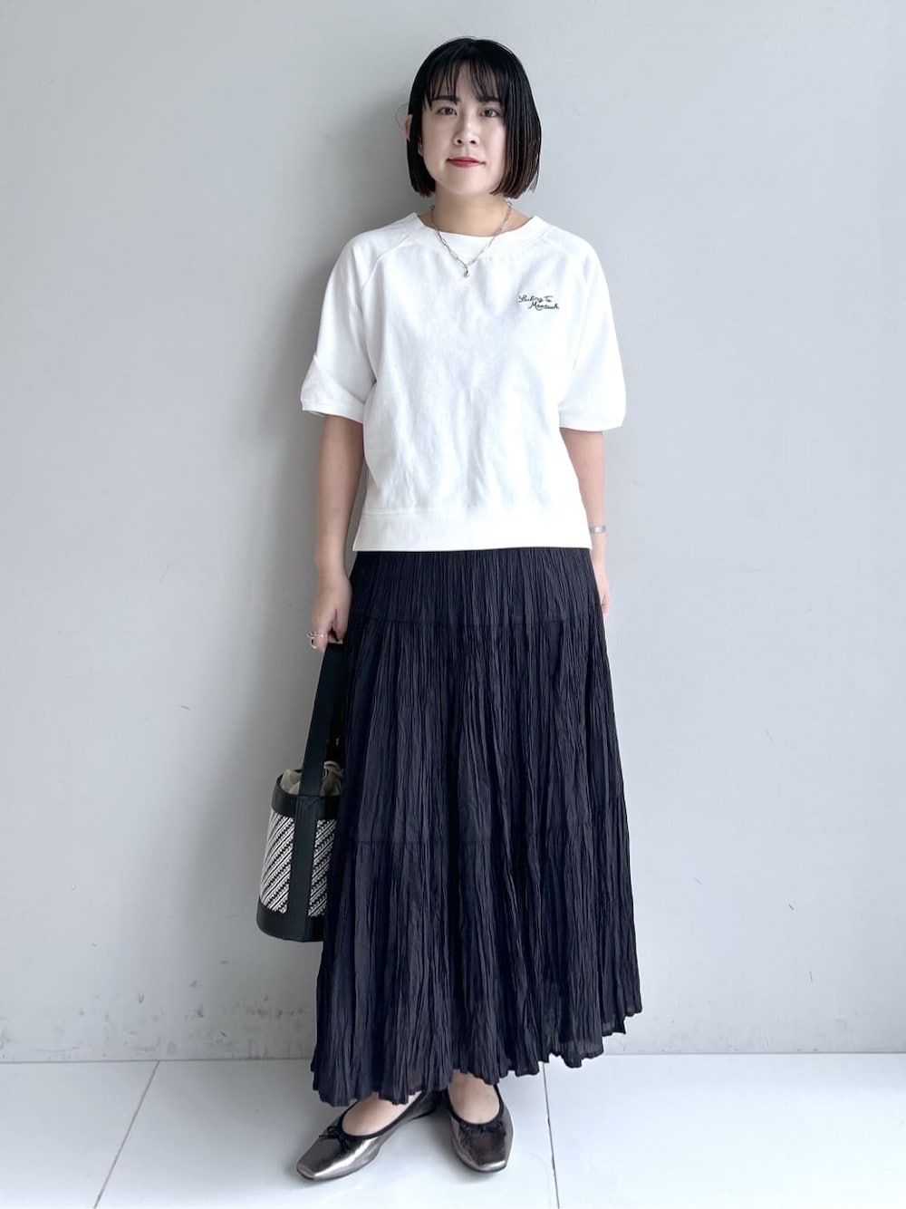 グレー系のカーディガン/ボレロ、ホワイト系のTシャツ/カットソー、ブラック系のスカートを着用したレディースの春コーディネートの1枚目の写真