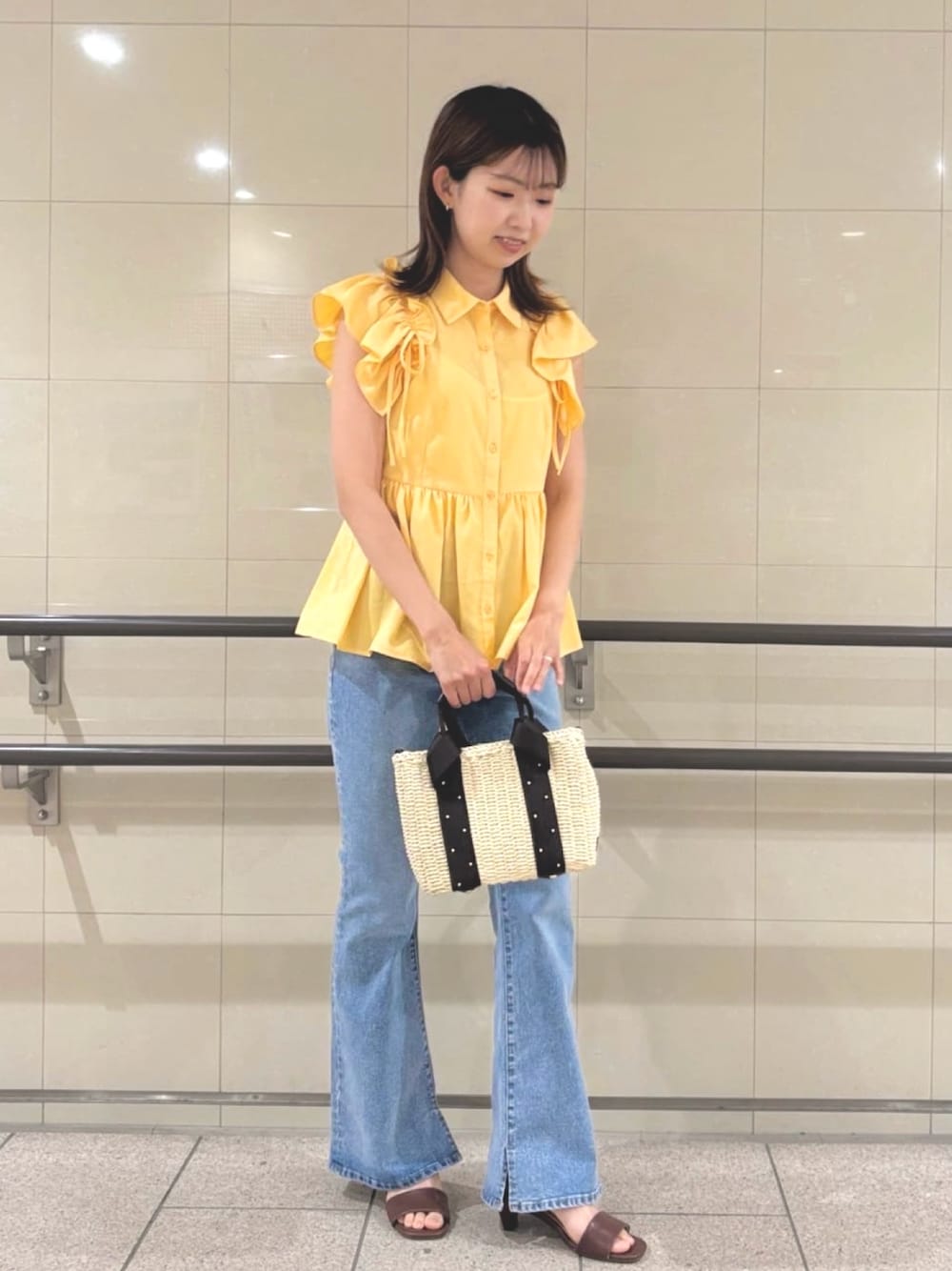 イエロー系のシャツ/ブラウス、ベージュ系のかごバッグ、ブルー系のデニムパンツを着用したレディースの夏コーディネートの1枚目の写真