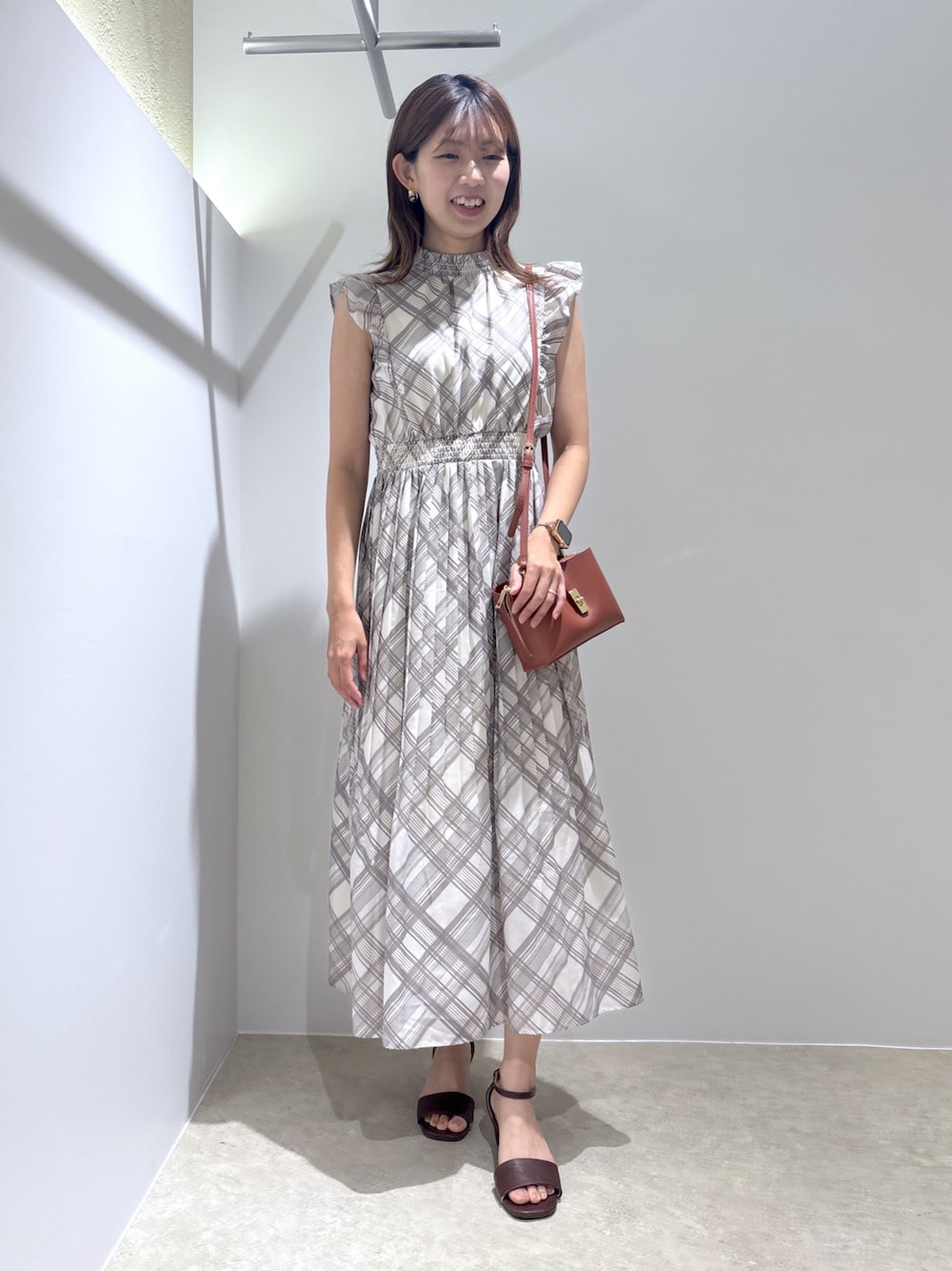 ベージュ系のワンピース、レッド系のショルダーバッグ、ブラウン系のサンダルを着用したレディースの夏コーディネートの1枚目の写真