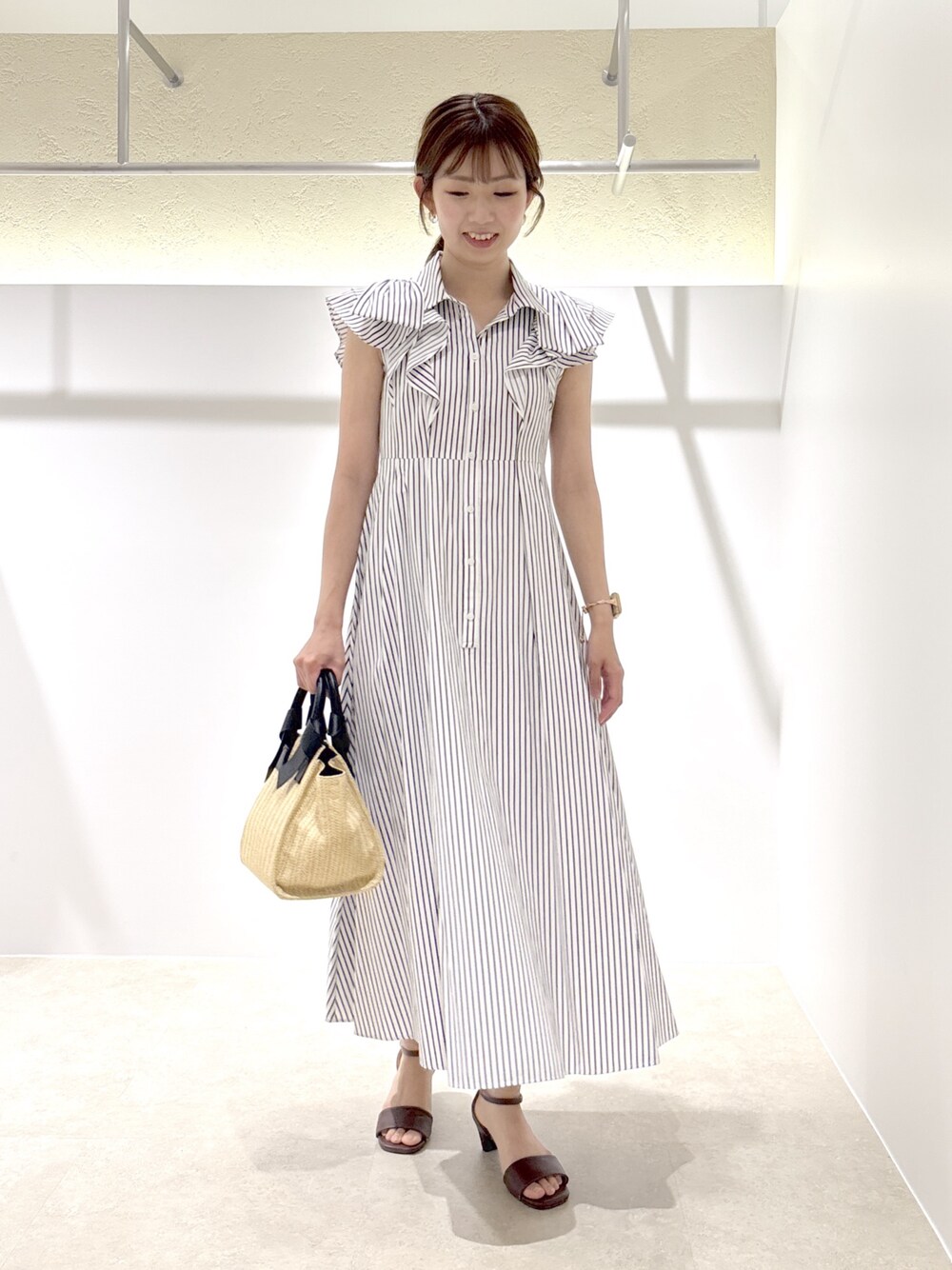 ホワイト系のワンピース、ベージュ系のトートバッグ、ブラウン系のサンダルを着用したレディースの夏コーディネートの1枚目の写真