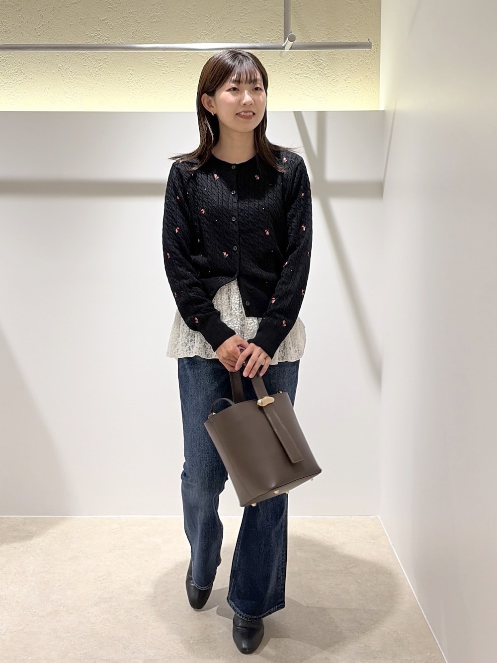 ブラック系のカーディガン/ボレロ、ホワイト系のTシャツ/カットソー、ブルー系のデニムパンツを着用したレディースの秋コーディネートの1枚目の写真