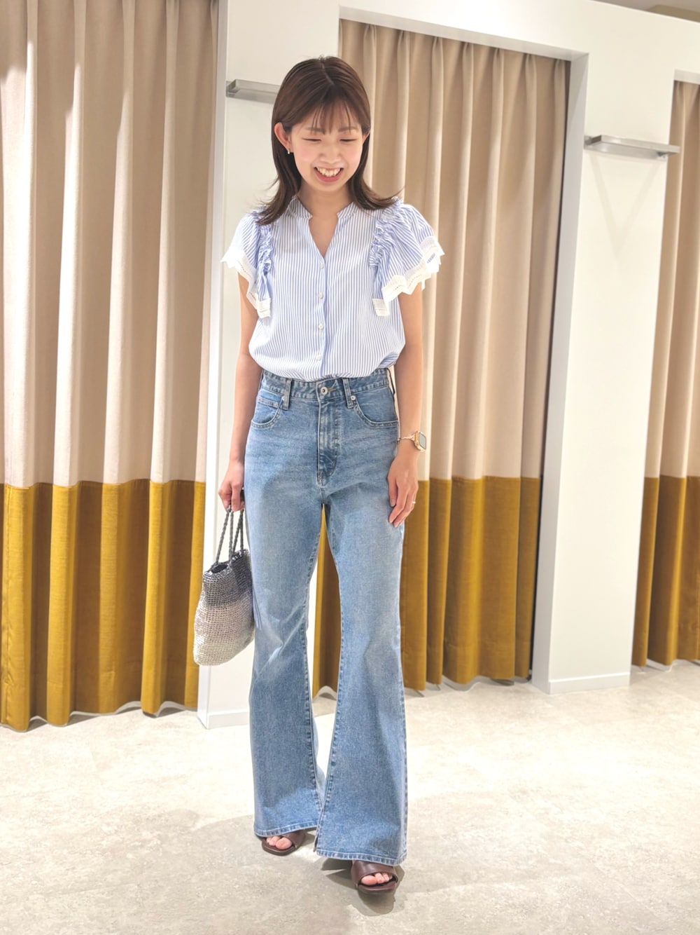 ブラウン系のサンダル、ブルー系のデニムパンツ、シルバー系のハンドバッグを着用したレディースの夏コーディネートの1枚目の写真