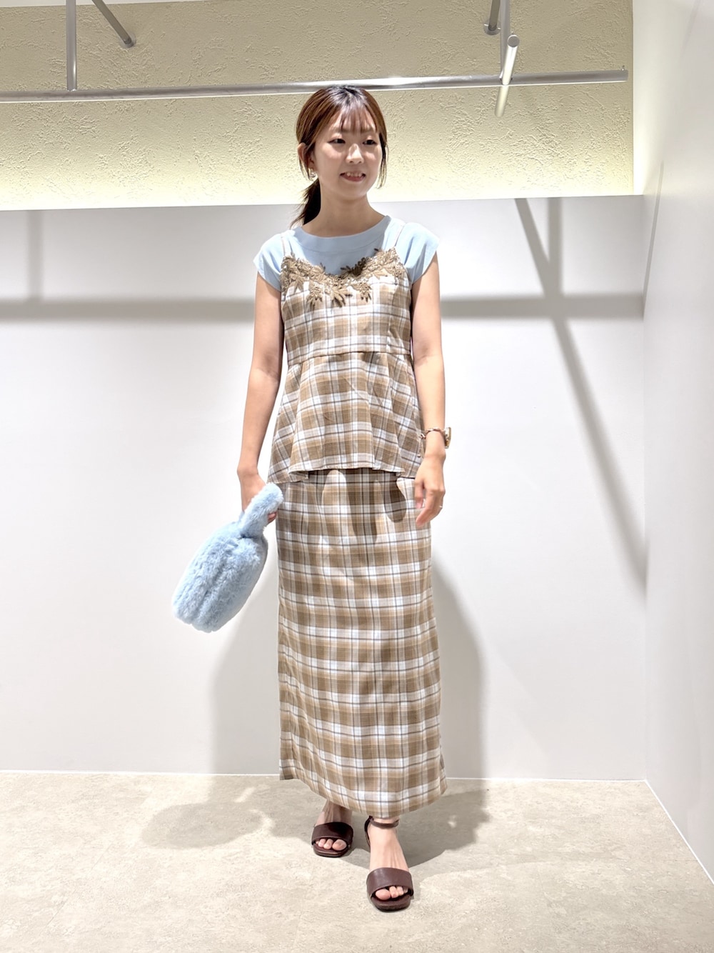ベージュ系のセットアップ、ブラウン系のサンダル、ブルー系のニット/セーターを着用したレディースの夏コーディネートの1枚目の写真