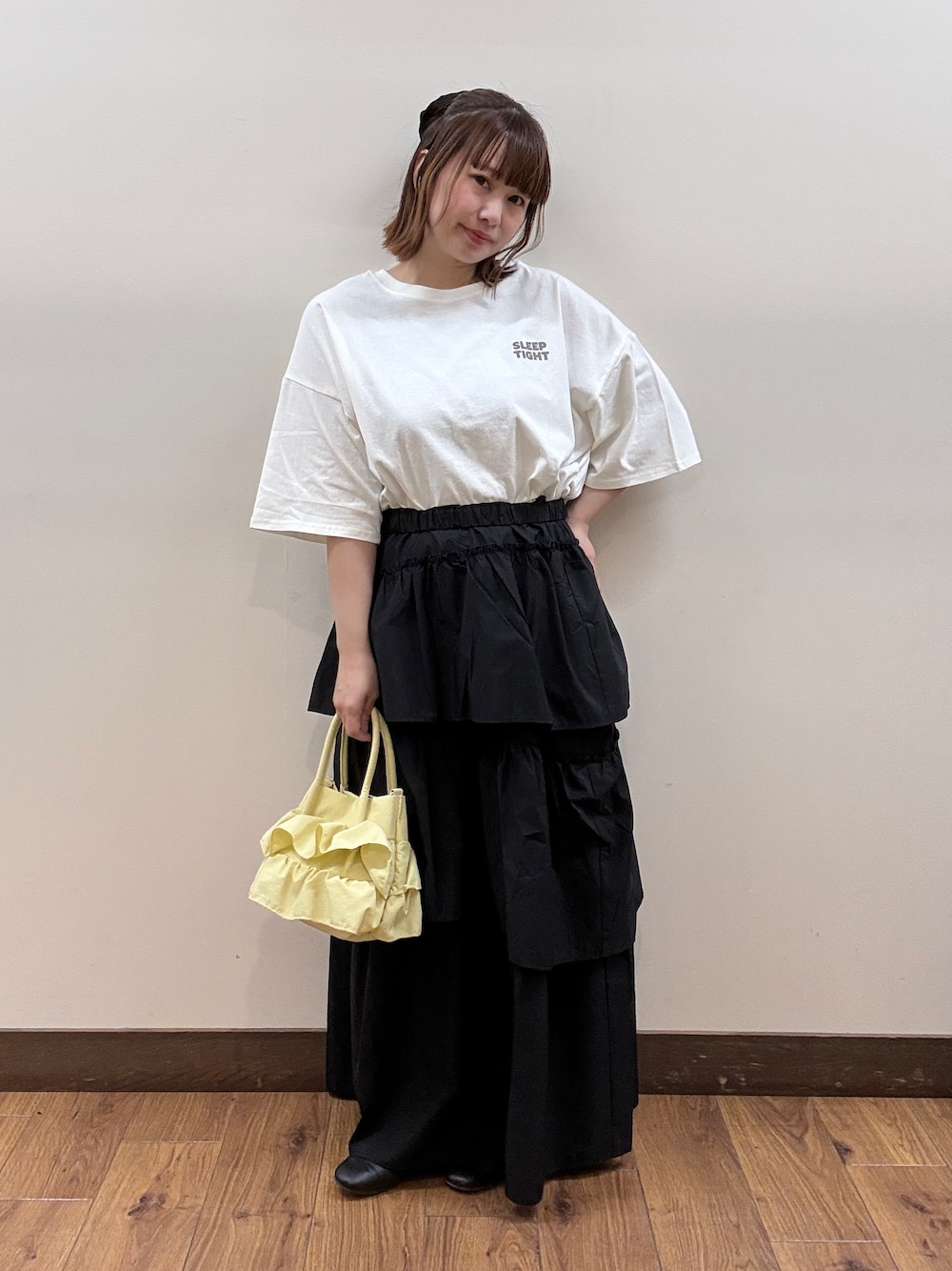 ホワイト系のTシャツ/カットソー、ブラック系のスカート、イエロー系のショルダーバッグを着用したレディースの春コーディネートの1枚目の写真