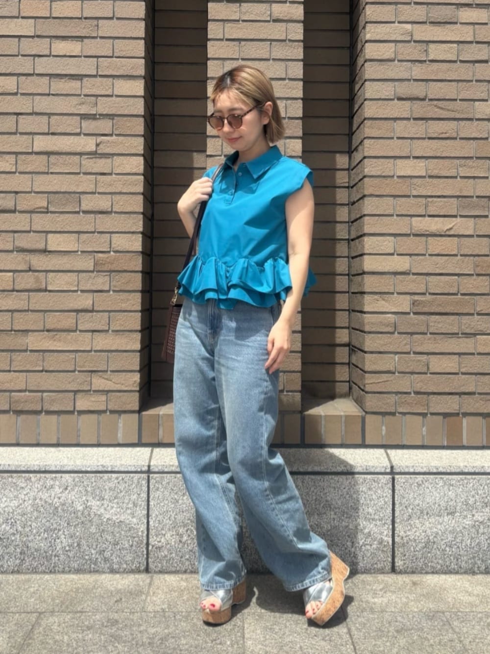 ブルー系のデニムパンツ、ブルー系のシャツ/ブラウス、オレンジ系のボストンバッグを着用したレディースの春コーディネートの1枚目の写真