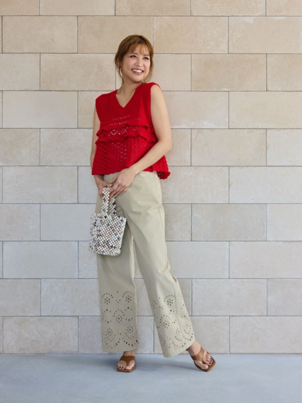 レッド系のニット/セーター、ベージュ系のその他パンツを着用したレディースの夏コーディネートの1枚目の写真