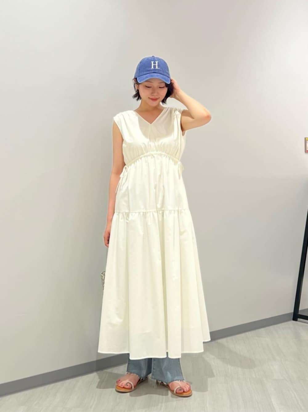 ブルー系のデニムパンツ、イエロー系のサンダル、ホワイト系のワンピースを着用したレディースの夏コーディネートの1枚目の写真