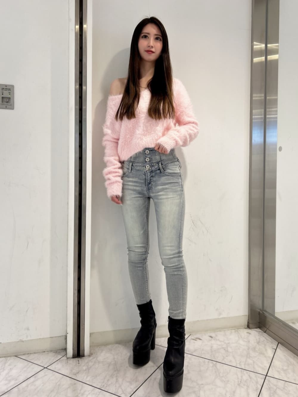 ブルー系のデニムパンツ、ピンク系のニット/セーター、ブラック系のブーツを着用したレディースの冬コーディネートの1枚目の写真