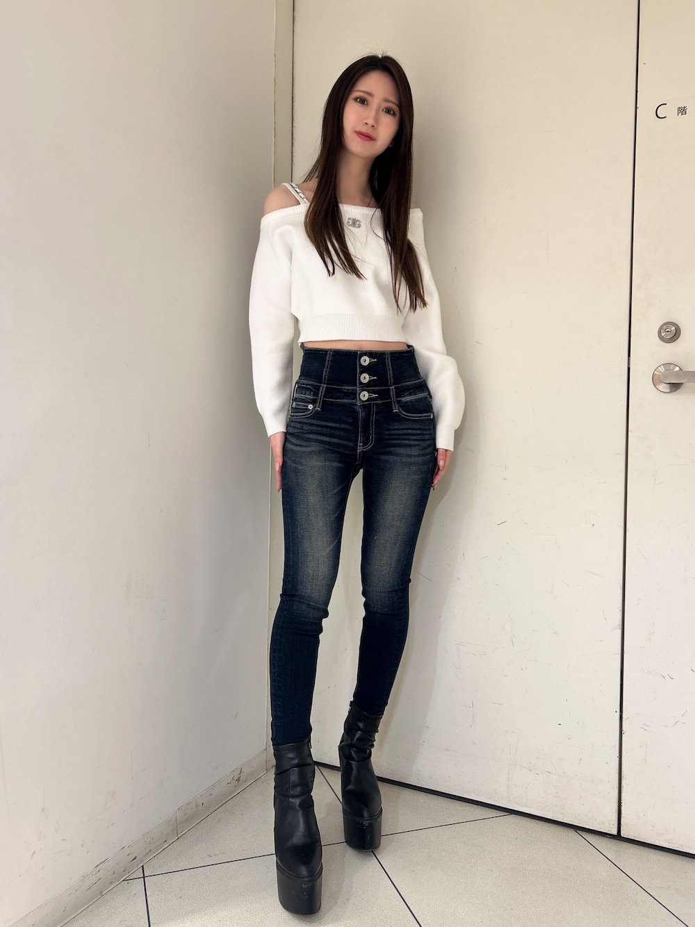 ホワイト系のニット/セーター、ブルー系のデニムパンツ、ブラック系のブーツを着用したレディースの冬コーディネートの1枚目の写真