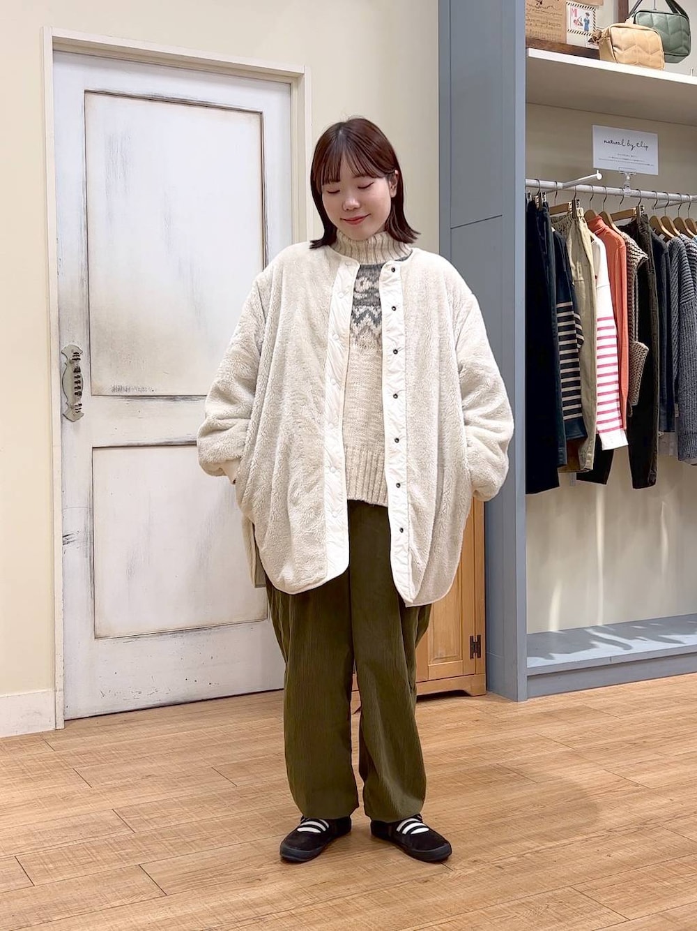 ホワイト系のノーカラーコート、グリーン系のその他パンツ、ブラウン系のスニーカーを着用したレディースの冬コーディネートの1枚目の写真