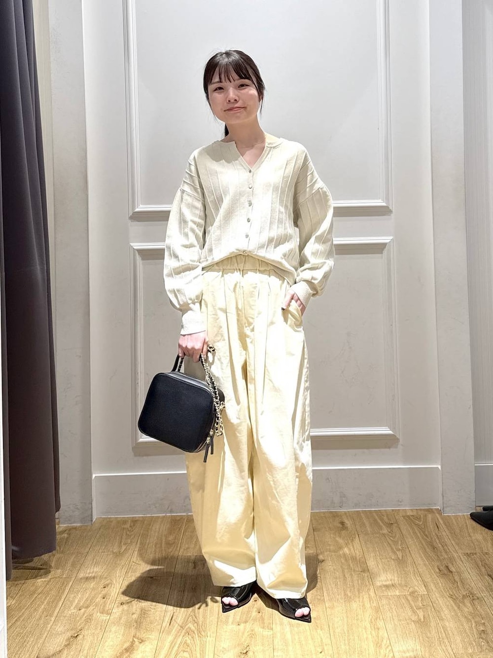 ホワイト系のカーディガン/ボレロ、ブラック系のサンダル、ブラック系のショルダーバッグを着用したレディースの春コーディネートの1枚目の写真