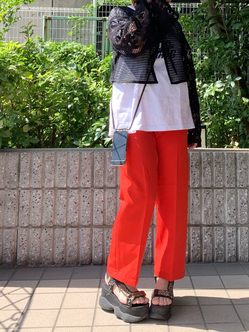 ブラック系のカーディガン/ボレロ、ホワイト系のトップス、レッド系のスラックスを着用したレディースの秋コーディネートの1枚目の写真