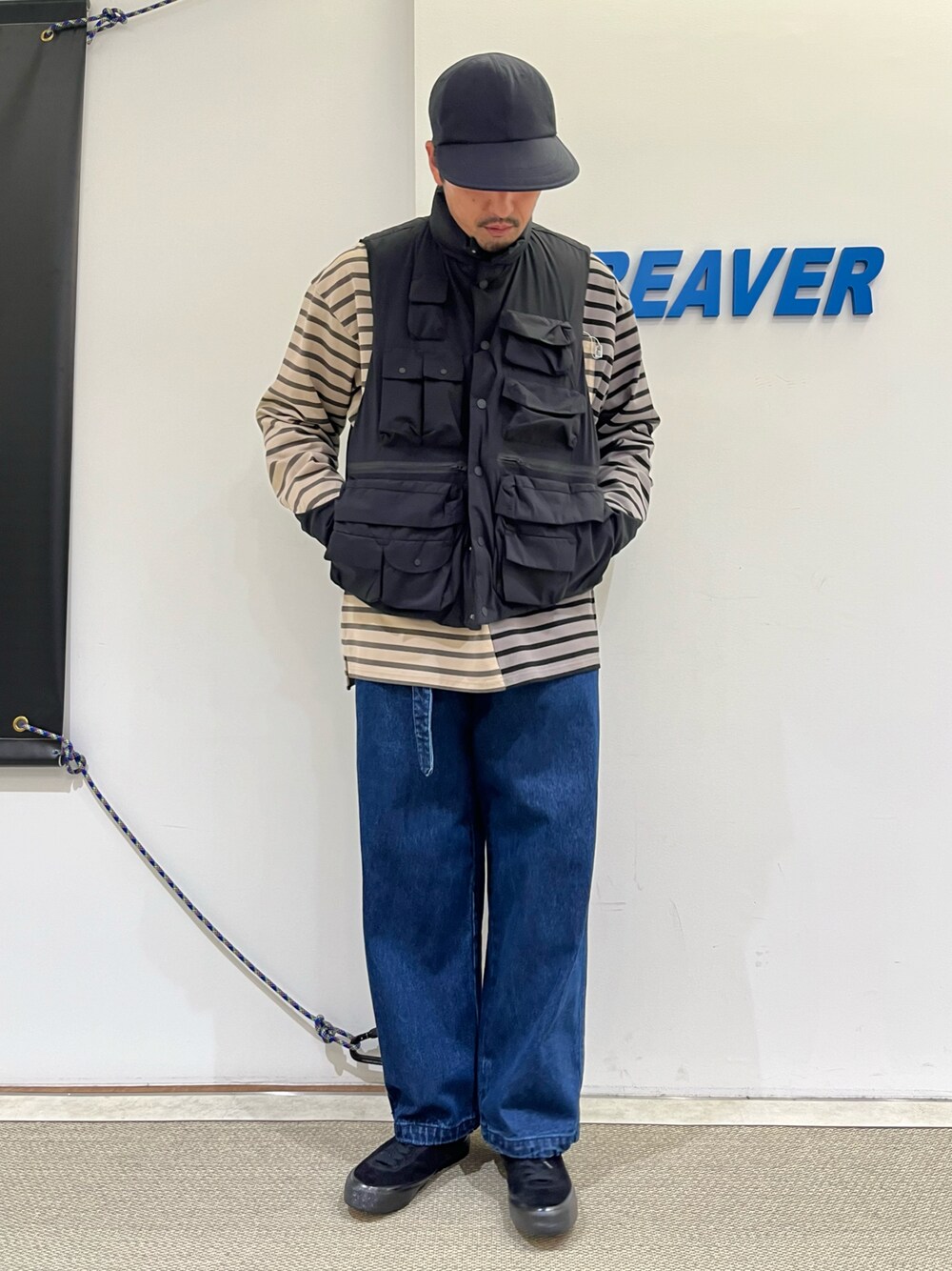 ブルー系のパンツ、ブラック系のTシャツ/カットソー、ブラック系のダウンベストを着用したメンズの秋コーディネートの1枚目の写真