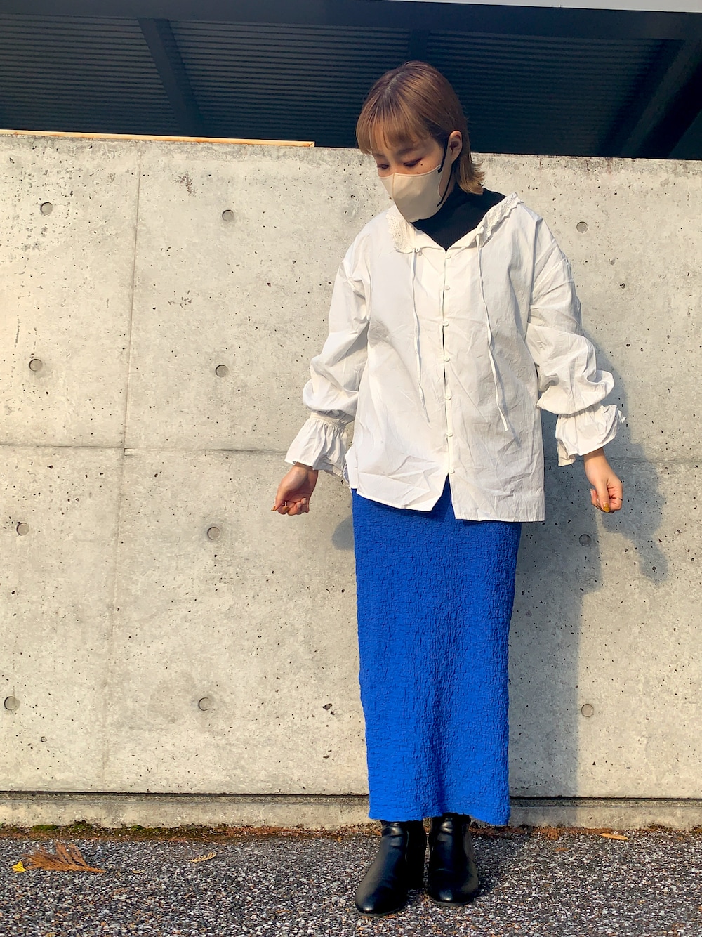 ブルー系のスカート、ホワイト系のシャツ/ブラウス、ブラック系のブーツを着用したレディースの秋コーディネートの1枚目の写真