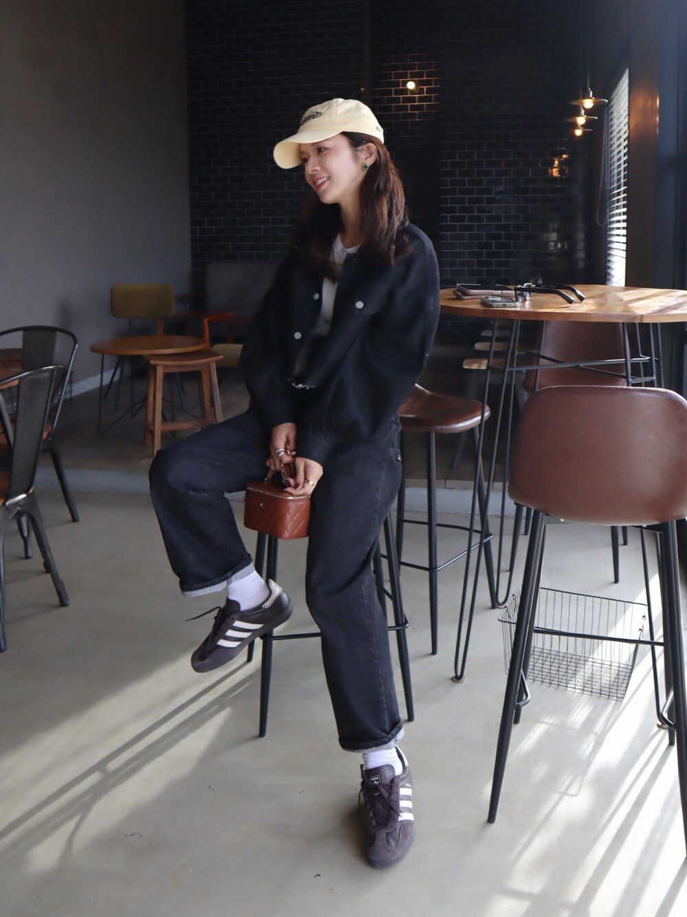 ブラウン系のスニーカー、ホワイト系のTシャツ/カットソー、ブラック系のデニムパンツを着用したレディースの冬コーディネートの1枚目の写真