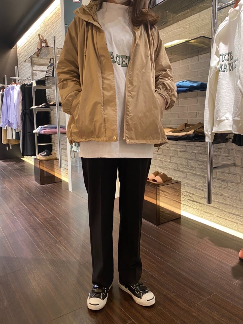 ベージュ系のマウンテンパーカー、ホワイト系のTシャツ/カットソー、ブラック系のパンツを着用したレディースの冬コーディネートの1枚目の写真