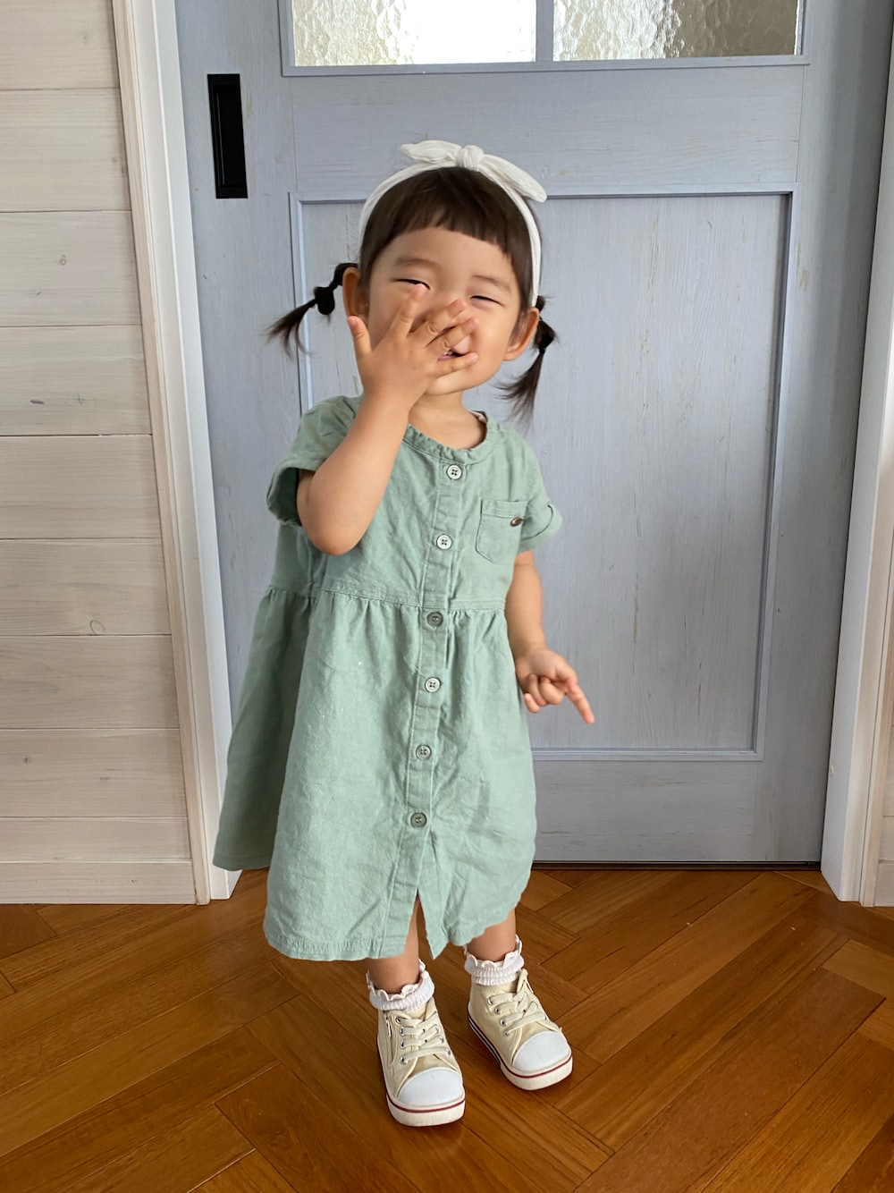 グリーン系のワンピース、ホワイト系のスニーカー、ホワイト系のヘアバンドを着用したキッズの春コーディネートの1枚目の写真