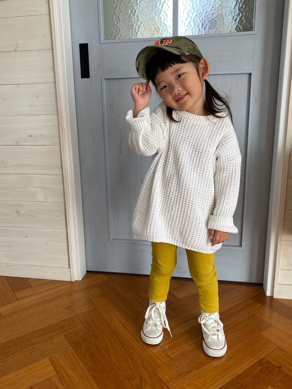 ホワイト系のスニーカー、イエロー系のパンツ、グリーン系のキャップを着用したキッズの春コーディネートの1枚目の写真