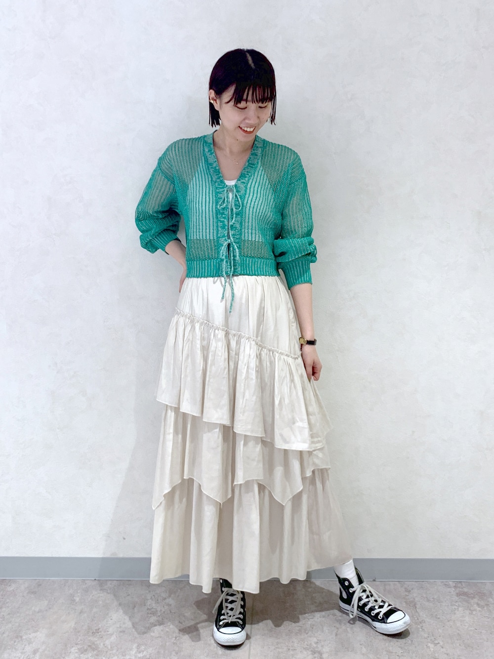 ベージュ系のスカート、ホワイト系のキャミソール、グリーン系のカーディガン/ボレロを着用したレディースの春コーディネートの1枚目の写真