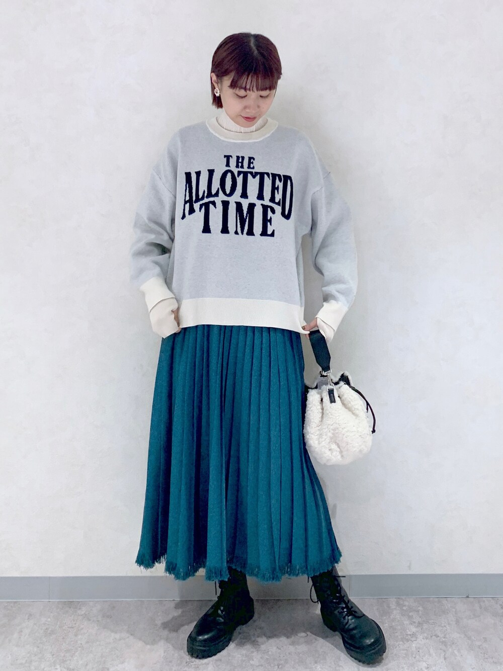 ホワイト系のニット/セーター、ブルー系のスカート、ブラック系のブーツを着用したレディースの秋コーディネートの1枚目の写真