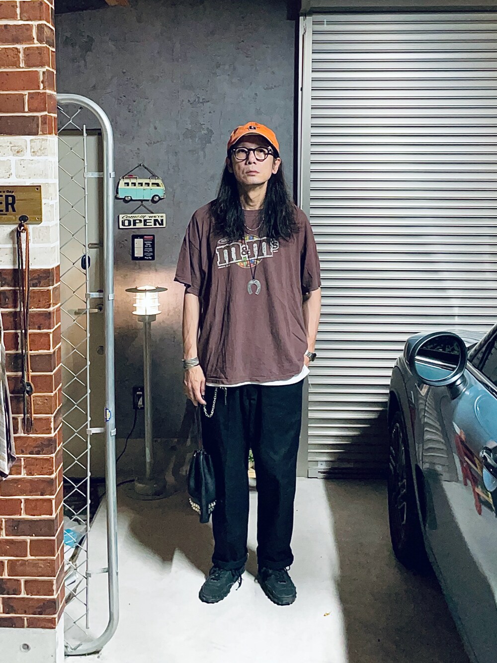 ブラック系のチノパンツ、ブラック系のバッグ、ブラック系のスニーカーを着用したメンズの夏コーディネートの1枚目の写真