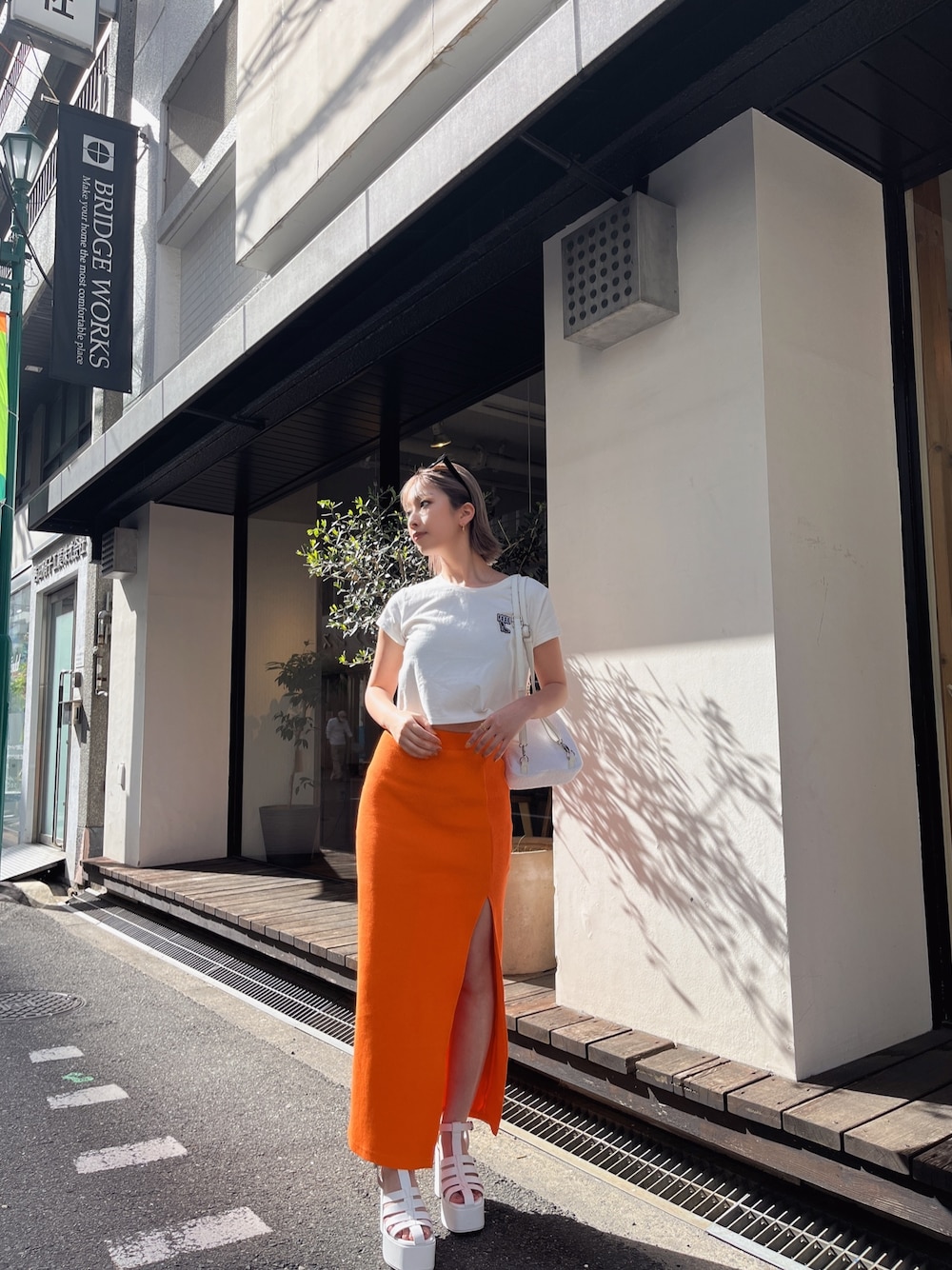 ホワイト系のTシャツ/カットソー、オレンジ系のスカートを着用したレディースの春コーディネートの1枚目の写真