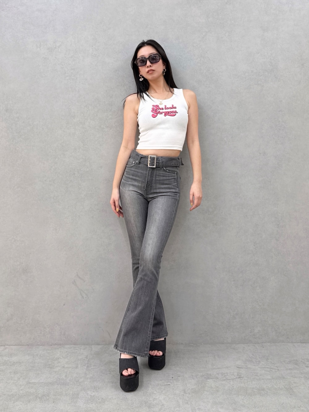 ブラック系のデニムパンツ、ホワイト系のタンクトップを着用したレディースの夏コーディネートの1枚目の写真