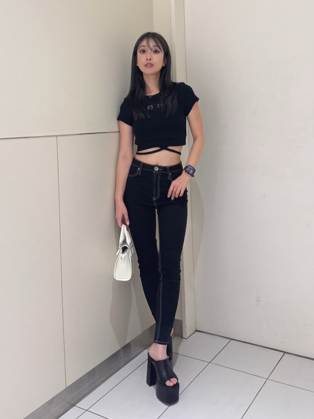 ブラック系のサンダル、ブラック系のハンドバッグ、ブラック系のデニムパンツを着用したレディースの夏コーディネートの1枚目の写真