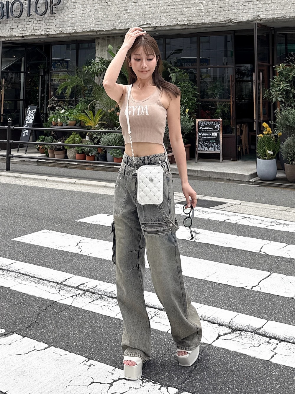 ベージュ系のキャミソール、ブルー系のデニムパンツ、ホワイト系のサンダルを着用したレディースの夏コーディネートの1枚目の写真
