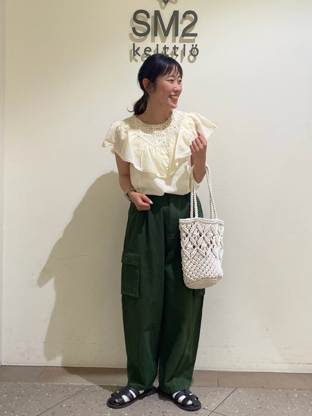 ホワイト系のトートバッグ、グリーン系のカーゴパンツ、ブラウン系のサンダルを着用したレディースの春コーディネートの1枚目の写真