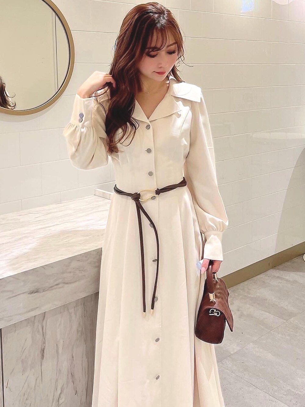 ホワイト系のワンピース、ブラウン系のハンドバッグ、ブラウン系のベルトを着用したレディースの冬コーディネートの1枚目の写真