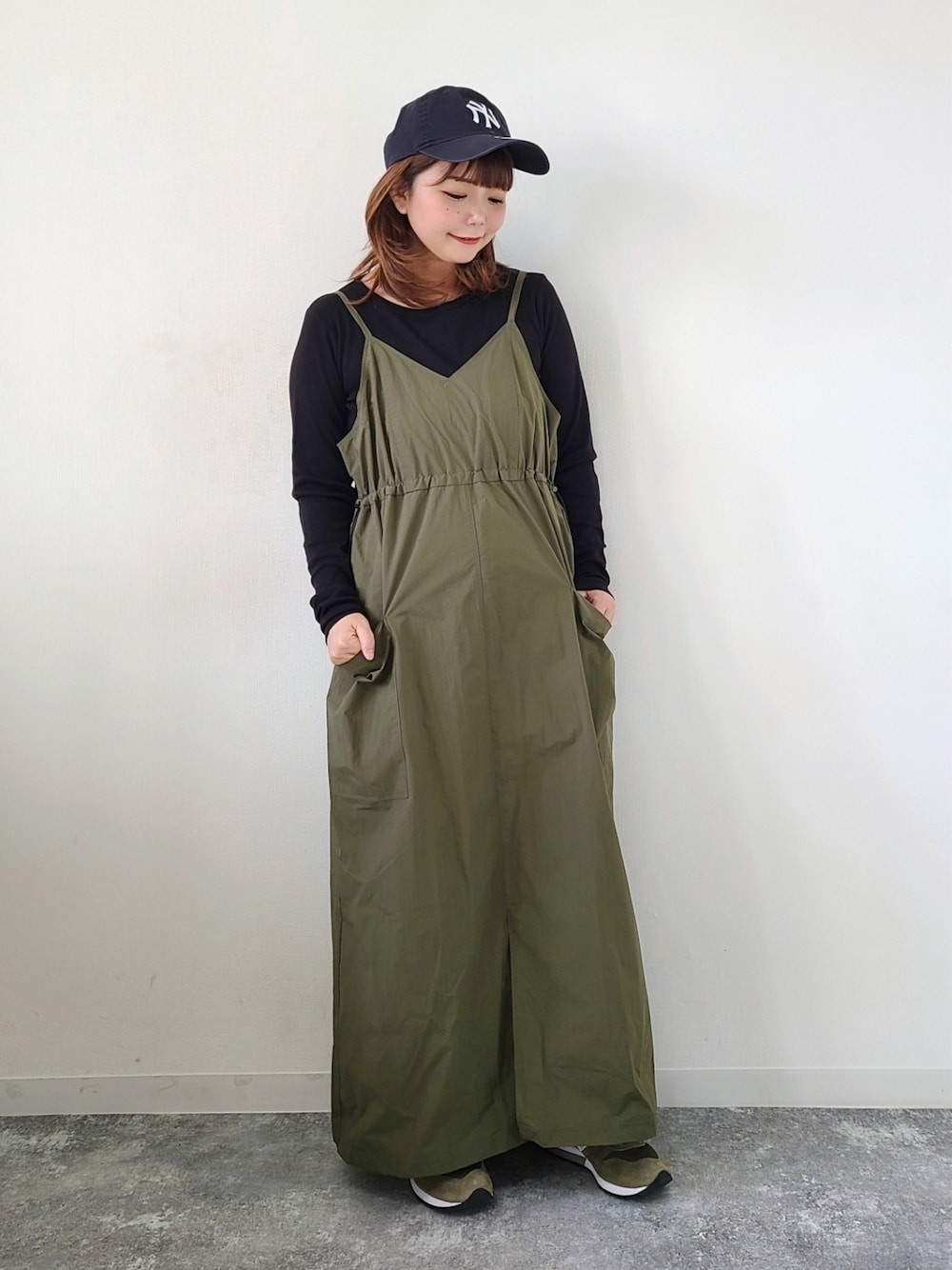 グリーン系のワンピース、ブラック系のTシャツ/カットソー、グリーン系のスニーカーを着用したレディースの秋コーディネートの1枚目の写真