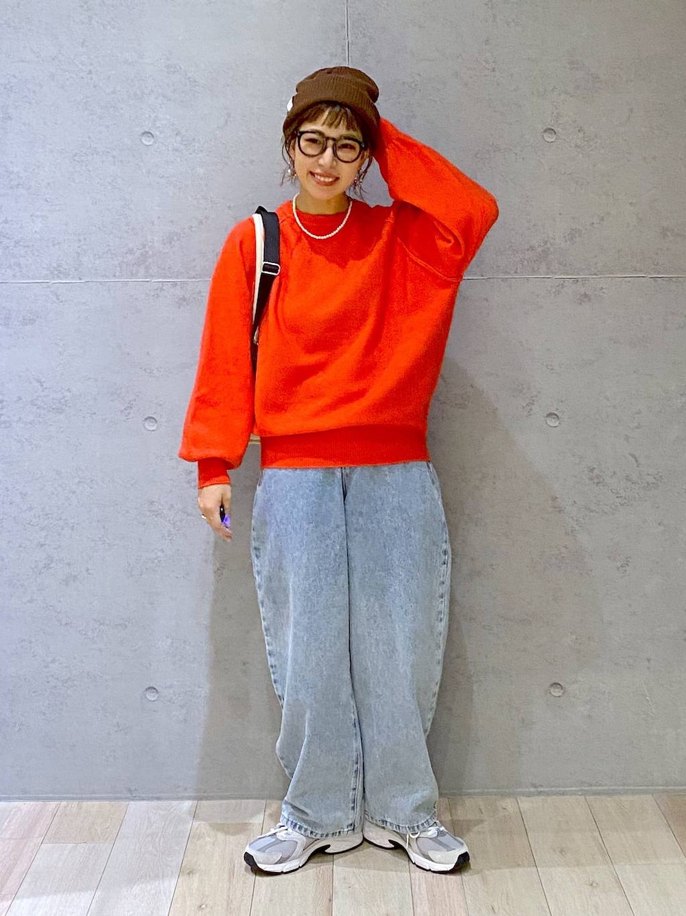 ホワイト系のショルダーバッグ、ブルー系のデニムパンツ、レッド系のニット/セーターを着用したレディースの秋コーディネートの1枚目の写真