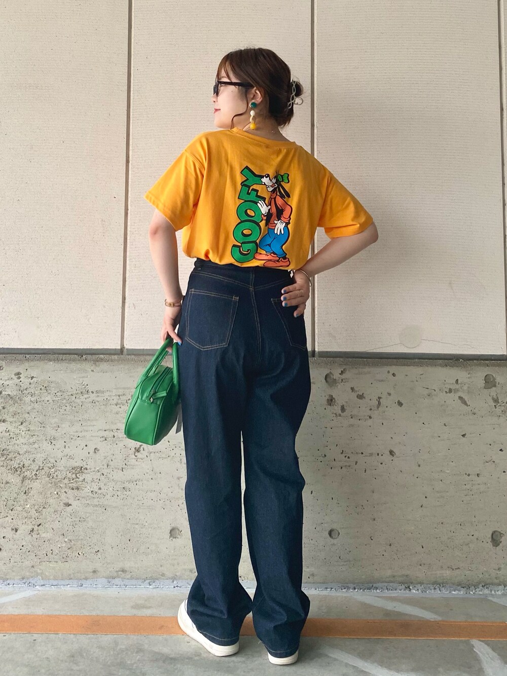 イエロー系のTシャツ/カットソー、ブルー系のデニムパンツ、グリーン系のショルダーバッグを着用したレディースの春コーディネートの1枚目の写真