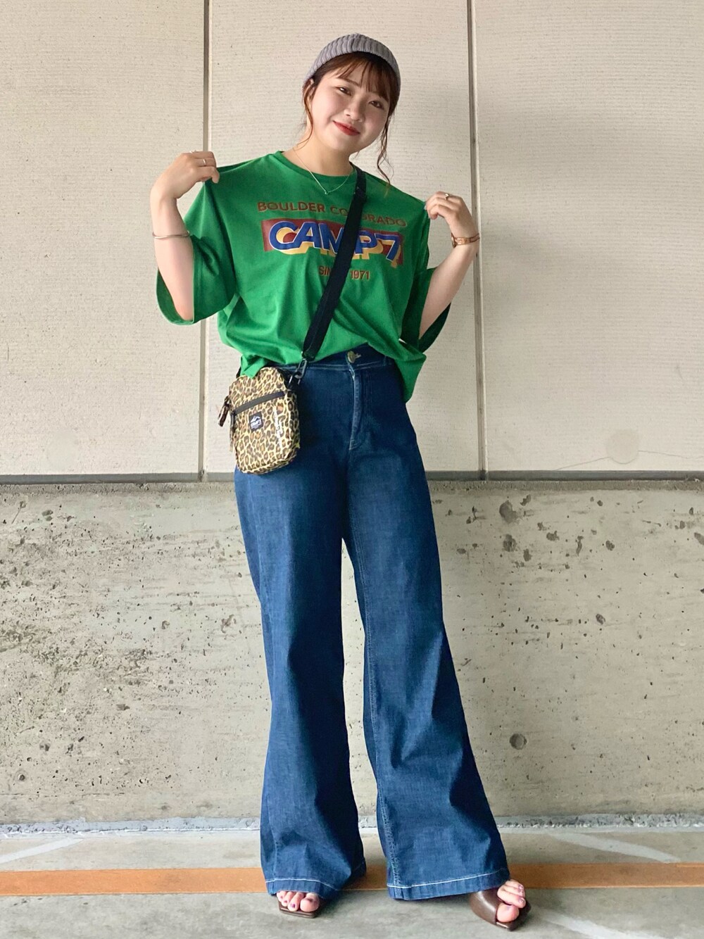 グリーン系のTシャツ/カットソー、ブルー系のデニムパンツ、ベージュ系のショルダーバッグを着用したレディースの夏コーディネートの1枚目の写真